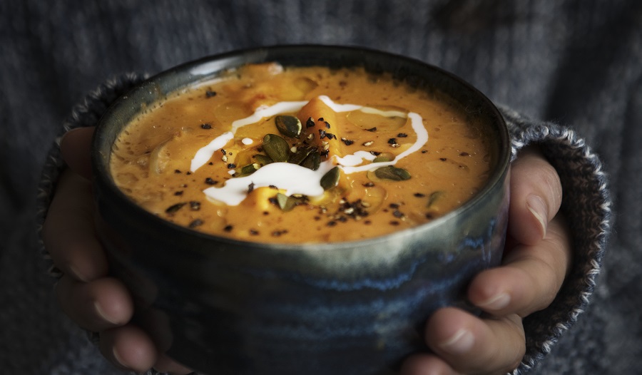 Mãos de uma mulher segurando um bowl com sopa para imunidade